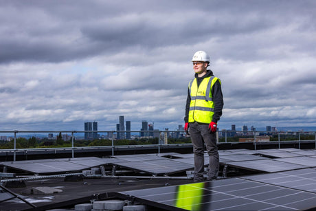A solar installer standing on a rooftop